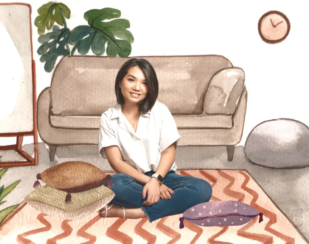 Shiela, the maker behind Sunshine and Petals, sitting cross-legged in her living room