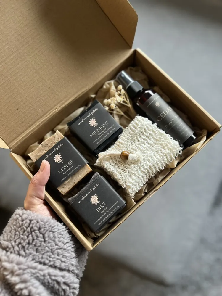 The Grounded Box opened to show three dark soap bars and a body oil